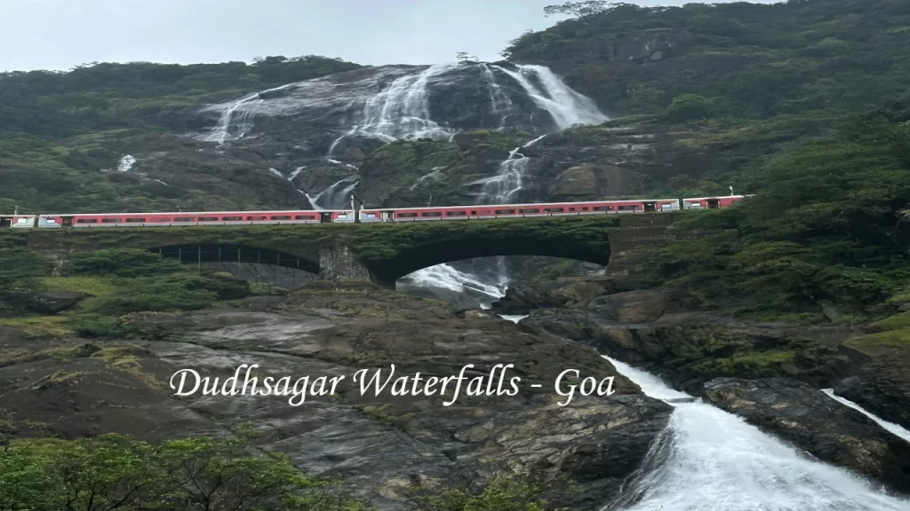 Dudhsagar Waterfalls with a red train crossing the railway bridge — a spectacular day trip destination for Goa with Family