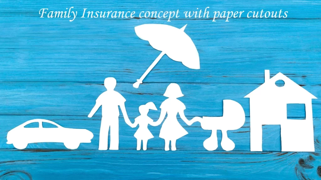 Family travel insurance concept – paper cutout of parents, children, car, pram and house under an umbrella on wooden background