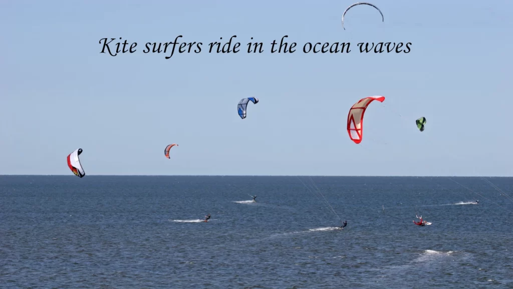 Several kitesurfers catching wind and riding ocean waves with colorful kites under a clear blue sky, highlighting outdoor water sports in Bentota.