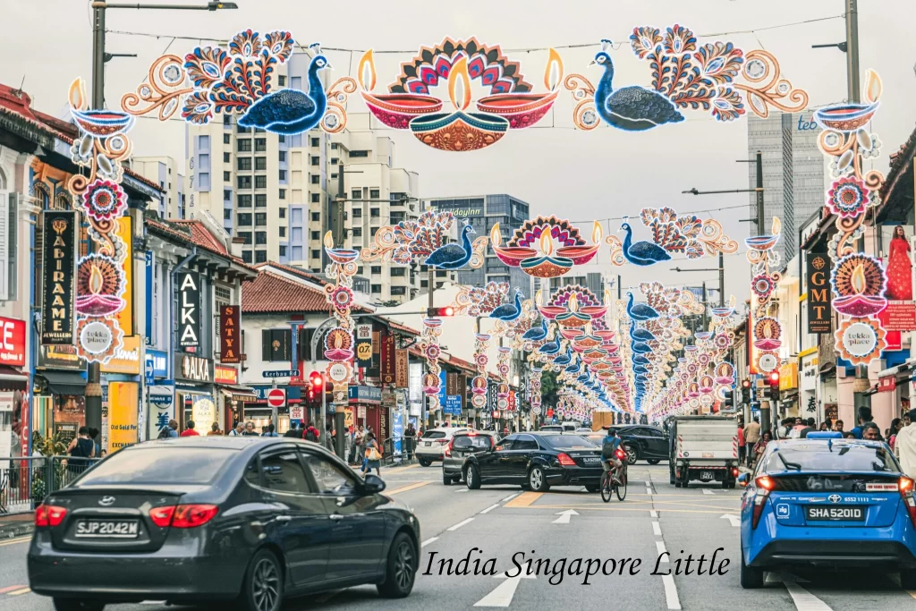 Bustling city street traffic passing beneath elaborate peacock-themed festive light arches in Little India, one of the liveliest places to visit in Singapore