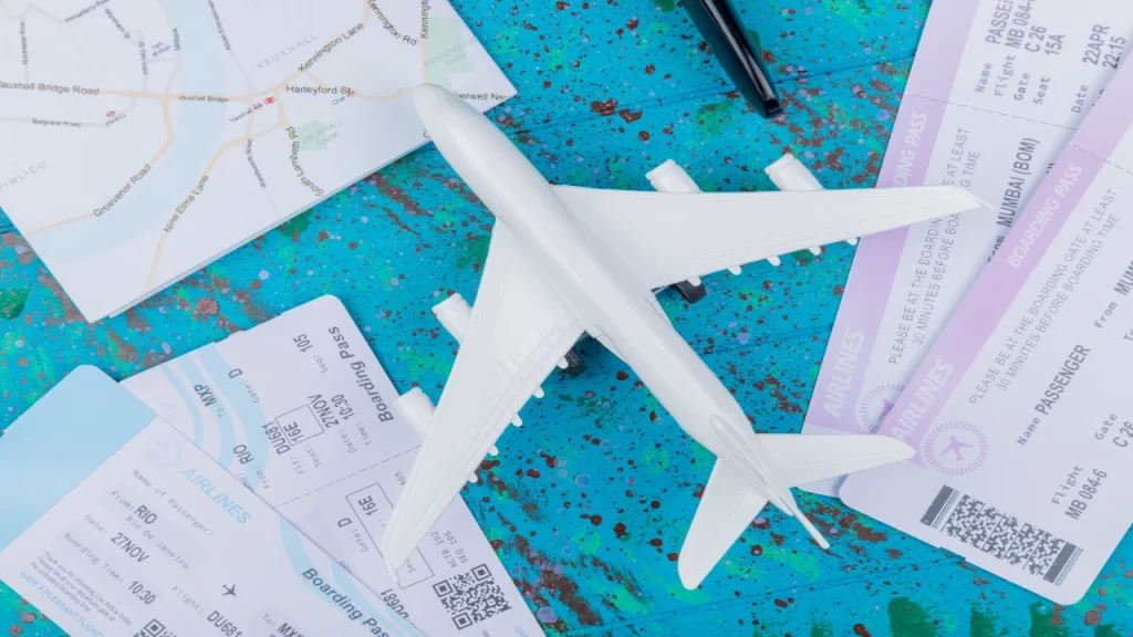 Flat lay of model airplane, boarding passes, and maps symbolizing international travel planning and flight booking tips and strategy.