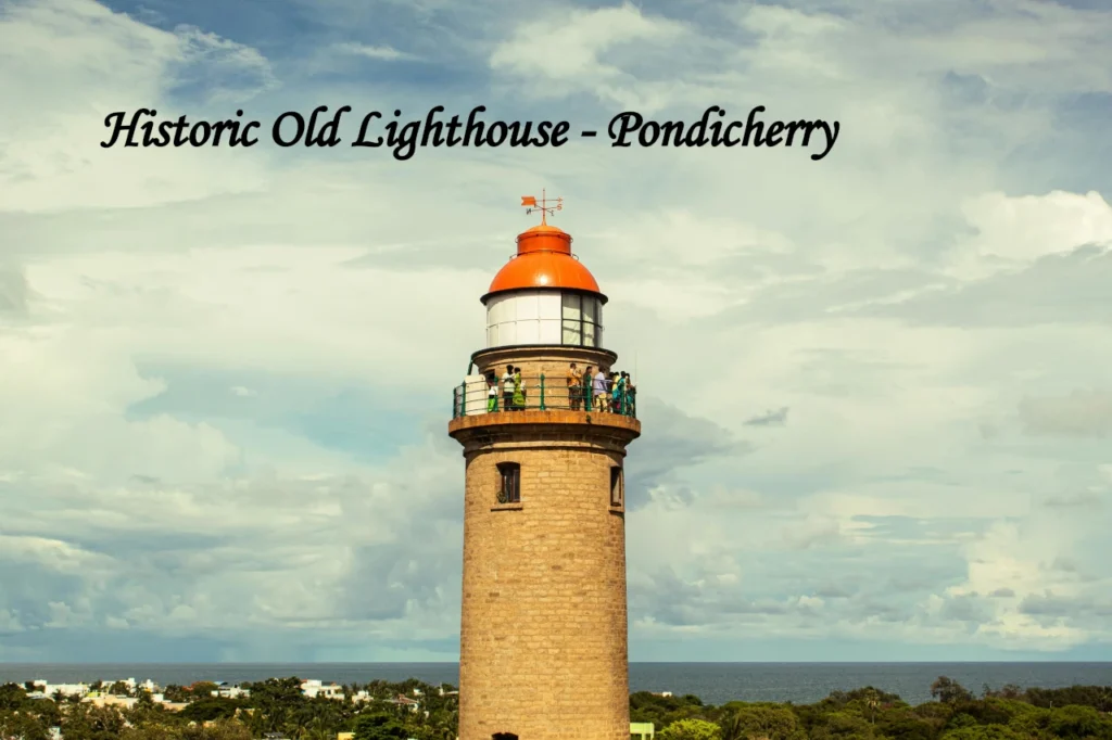 The historic stone lighthouse with a red dome and a viewing deck full of tourists, one of the iconic architectural places to visit in Pondicherry.