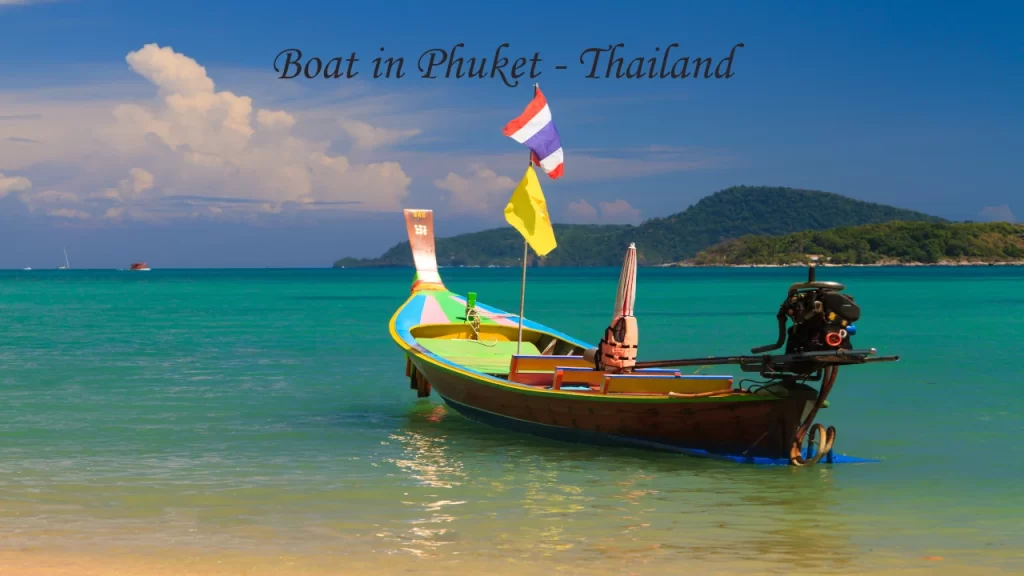Colourful Thai longtail boat with Thai flag on turquoise waters in Phuket, Thailand — a popular destination wedding location in Asia