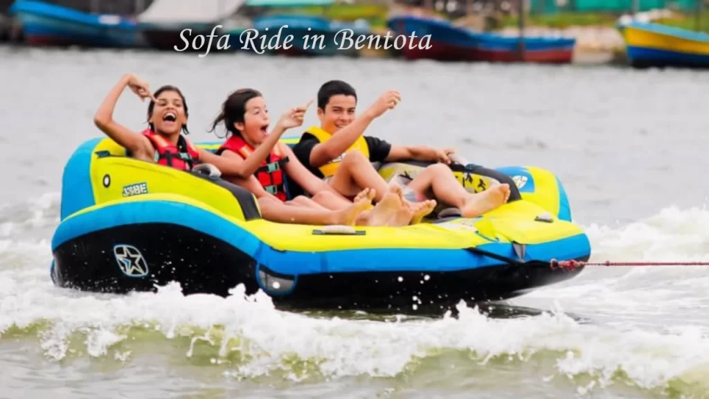 Three excited young people wearing life jackets enjoying a thrilling towed sofa ride on the water, highlighting fun group water sports in Bentota.