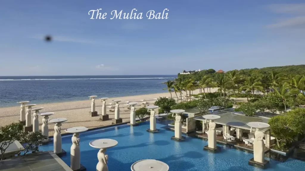 The iconic beachfront Oasis Pool at The Mulia Bali in Nusa Dua, lined with majestic statues overlooking the ocean—one of the top luxury places to visit in Bali.