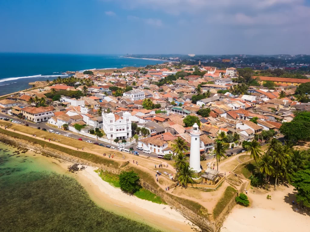 Visitors exploring cobblestone lanes of Old Galle Fort, a UNESCO Heritage Site in Sri Lanka, with colonial Dutch buildings and ocean ramparts in the background