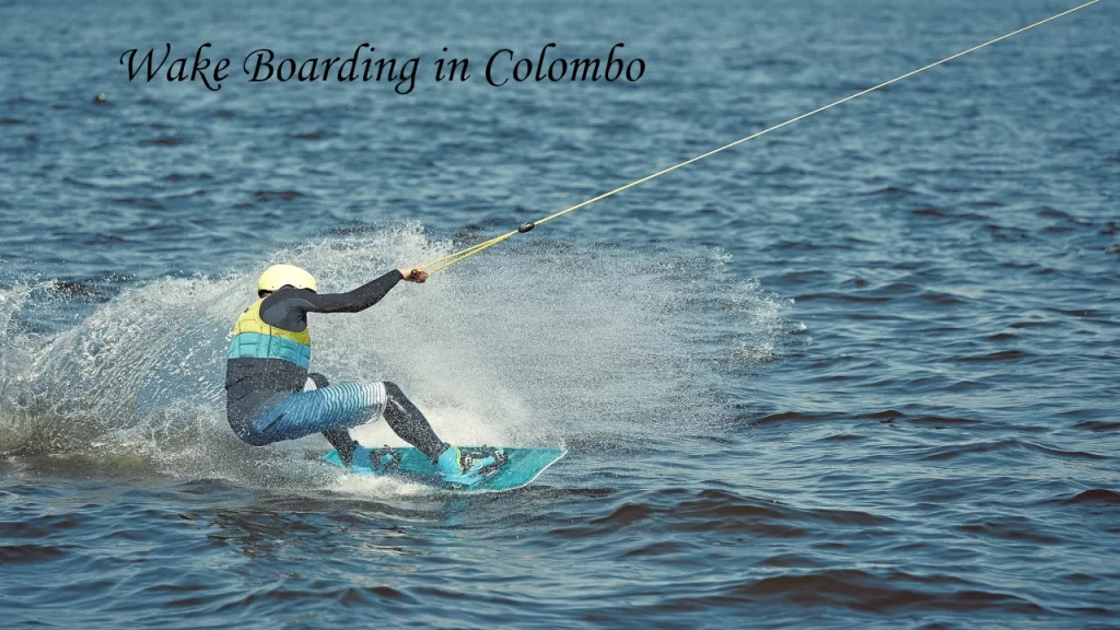 A wakeboarder wearing a helmet and life jacket carving through the water, creating a big splash while wakeboarding in Colombo, Sri Lanka.