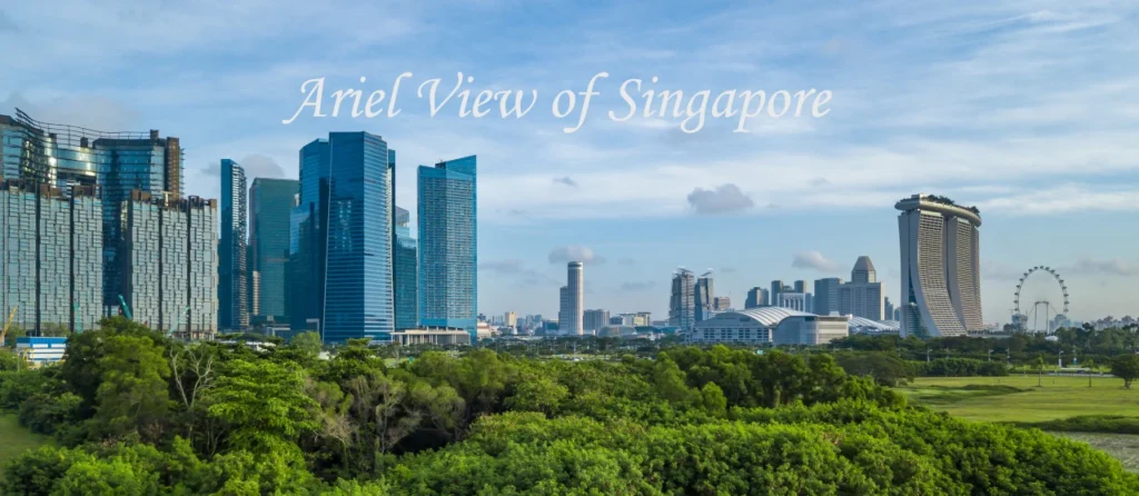 Panoramic daytime aerial view of the modern skyscrapers and green spaces that define the iconic places to visit in Singapore.