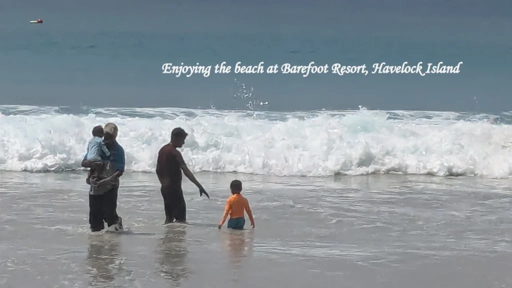 A family with young children playing in the waves near the shore, showcasing relaxing beachside tourist activities in Havelock Island during a stay at Barefoot Resort