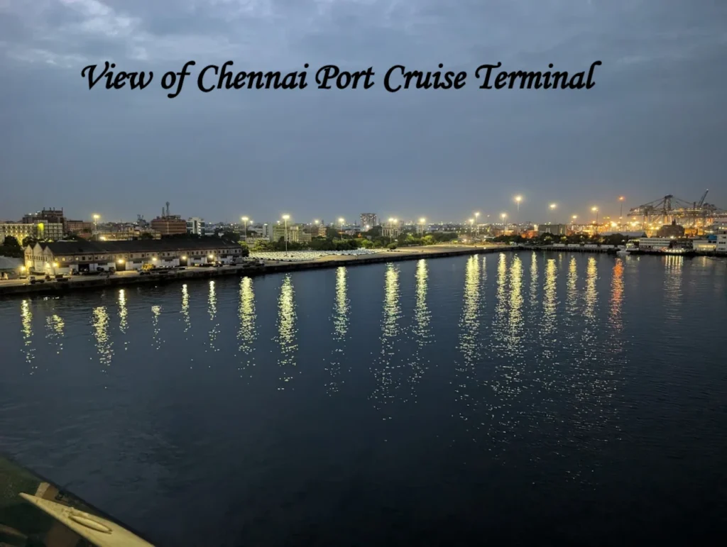 A scenic night view of the illuminated Chennai Port Cruise terminal taken from the water, showing city lights reflecting on the sea.