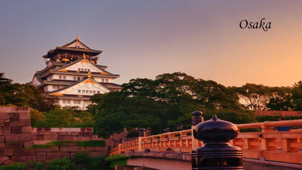 Osaka Castle overlooking green gardens and a wooden bridge at sunset, a memorable highlight of a 7 days tour in Japan.