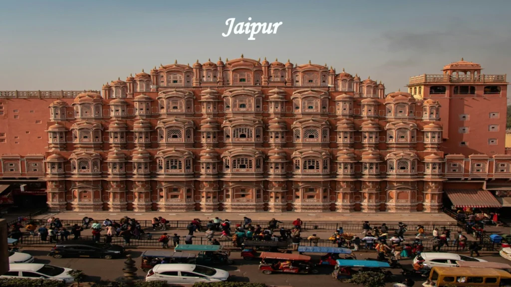 Indian Travel destination featuring Jaipur's iconic Hawa Mahal with its pink sandstone façade, intricate windows, bustling streets, and vibrant heritage.