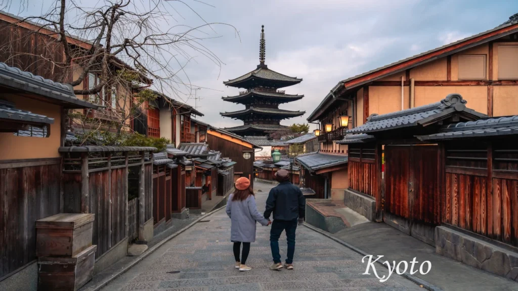 A couple holding hands and walking along a historic cobblestone street toward Yasaka Pagoda in Kyoto during a 7 days tour in Japan.