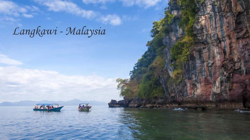 Tourist boats exploring towering karst limestone cliffs on the calm waters of Langkawi, Malaysia a secluded destination wedding location in Asia
