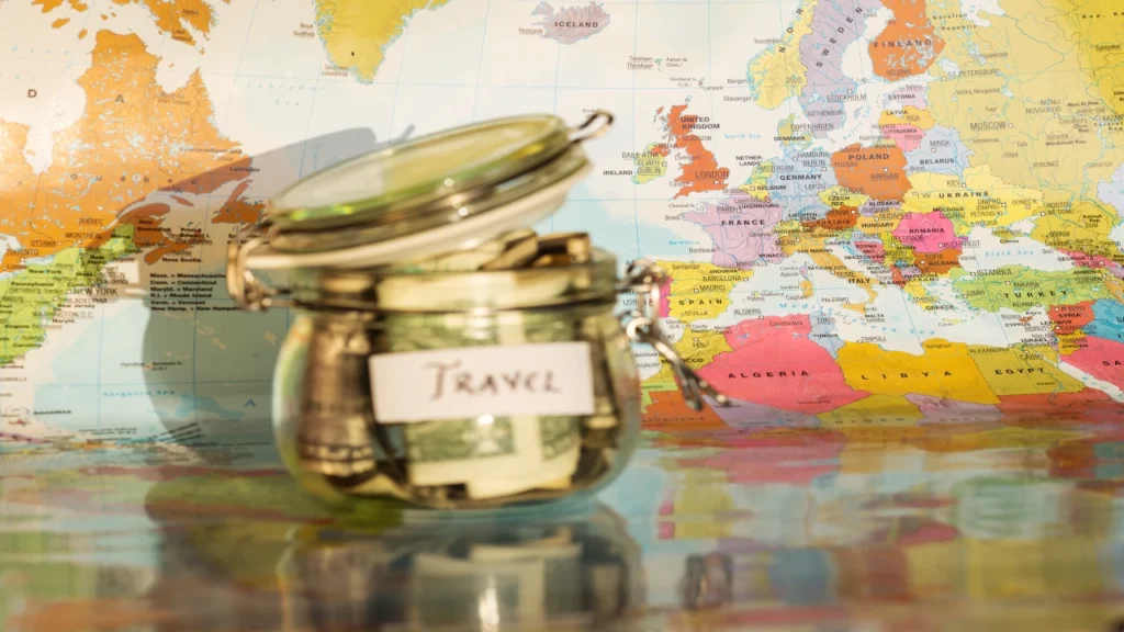 Clear glass jar labeled Travel filled with cash savings on a colorful map of Europe, representing funds ready for Forex cards.