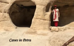 Woman standing inside one of the ancient rock-cut sandstone caves in Petra, Jordan.