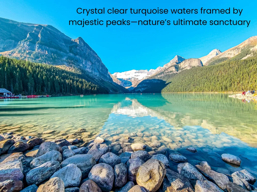 Close-up of crystal-clear turquoise water at Lake Louise's rocky shoreline with mountains in the background