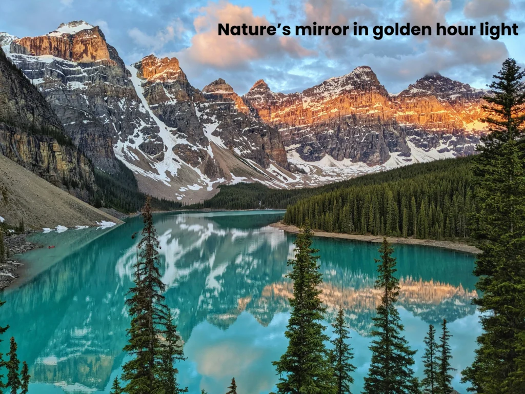 Sunset golden light illuminating snow-capped mountain peaks reflected on the calm turquoise surface of Moraine Lake.